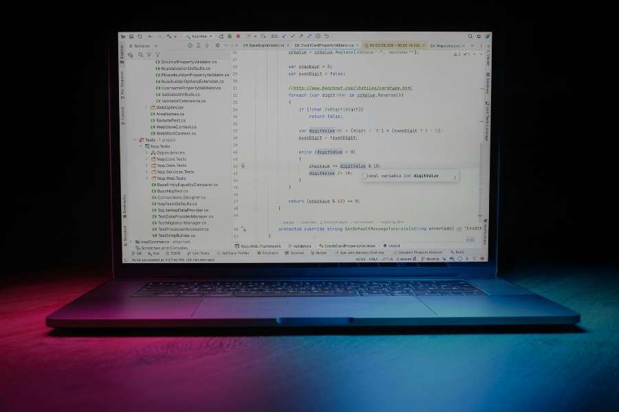 Un ordinateur portable ouvert affichant des lignes de code informatique dans une ambiance sombre.