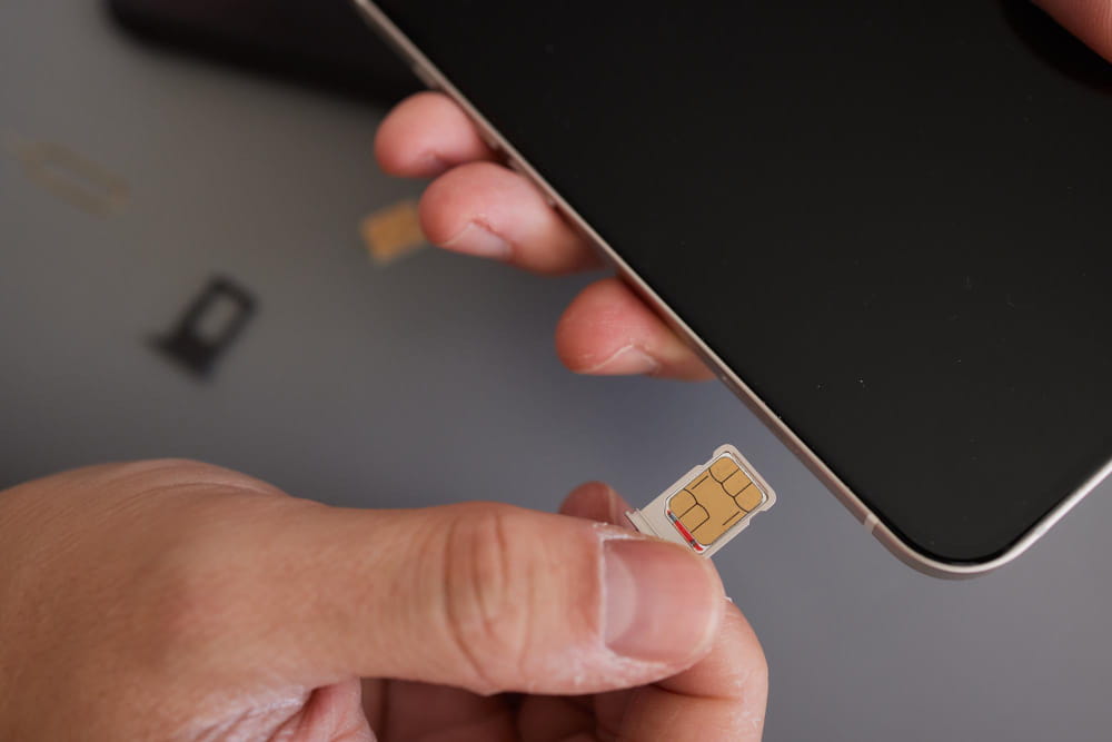 Une personne insérant une petite carte sim dans le tiroir d'un smartphone moderne.
