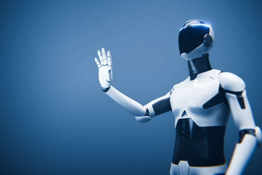 Un robot humanoïde blanc et noir lève la main pour saluer, incarnant le concept des assistants intelligents.